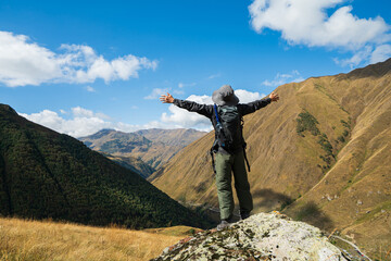 Climber raising arms in joy while celebrating achievement on a mountain peak in Juta Village,...