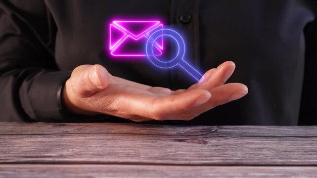 Searching and reviewing emails. Close-up of a woman's hand on a table holding a virtual icon of a mail envelope with a magnifying glass.
