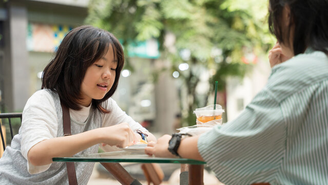 A girl enjoying dessert with a friend at an outdoor cafe. - Powered by Adobe