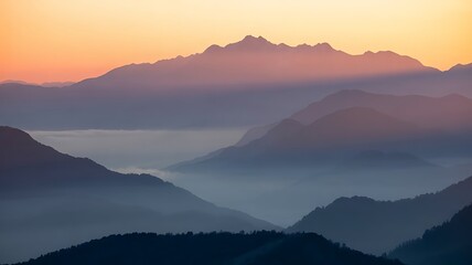 Majestic mountain range at sunrise with soft orange sky and mist landscape
