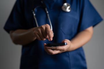 Close-up of doctor in scrubs using smartphone, showing digital healthcare communication, mobile technology in medicine, telehealth, and modern tools for online consultation and patient data access.