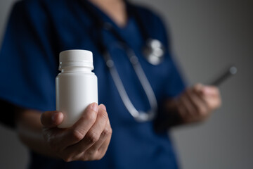 Doctor holding white pill bottle and smartphone, symbolizing prescription, digital healthcare services, remote consultation, modern medicine distribution and mobile pharmaceutical management systems.