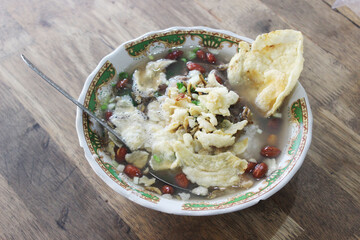 Traditional Indonesian bubur ayam with fried shallots and toppings.