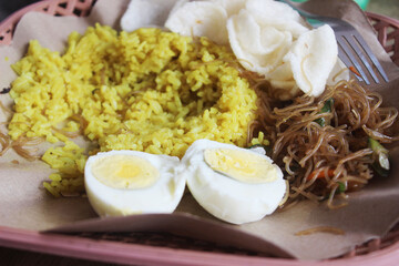 Traditional Indonesian yellow rice dish with side dishes.