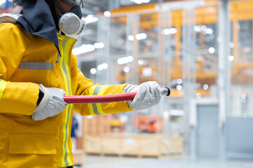 Firefighter holding hose ready to extinguish fire in factory warehouse