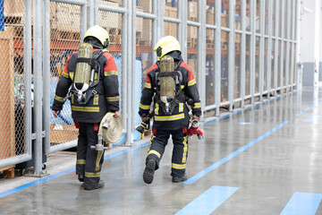 Team of firefighters walking with equipment in an industrial warehouse