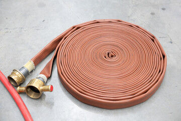 Coiled brown fire hose with brass coupling on concrete floor