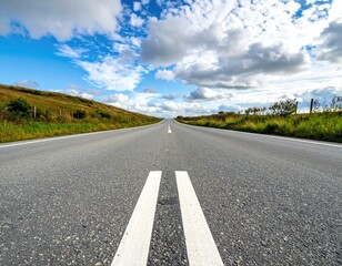 Empty asphalt road extends toward horizon under cloudy sky
