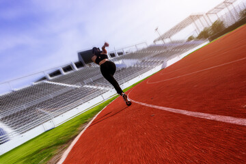 Silhouette of fit young woman running sprinting at the racetrack. Fit runner fitness runner during outdoor workout at racetrack with high speed zoom blur effect.