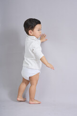 The child stands with arms slightly raised.