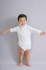 The child stands reaching sideways.