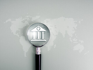Magnifying glass focusing on bank icon over world map, representing global online banking, currency exchange, digital finance, fintech, and international money transfer in the digital economy.