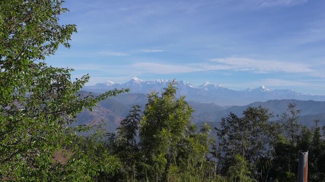 Panoramic wide shot of Himalayan snow-capped mountain range with lush green forest foreground, Almora Uttarakhand India 4K