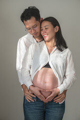 Couple embracing and showing pregnant belly in casual home setting