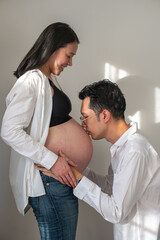 Man kissing pregnant woman belly at home maternity love and connection