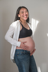 Pregnant woman smiling and holding belly in casual home setting