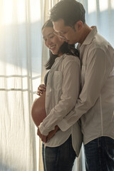 Couple embracing and expecting baby at home with natural light