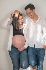 Happy couple expecting baby posing together in casual clothes at home
