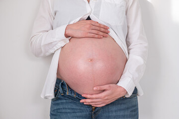 Pregnant woman holding belly in casual clothing at home