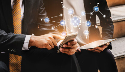 Two business professionals engage in digital communication with smartphones and tablets, highlighting innovation, technology, and collaboration in a modern workspace. Tessel