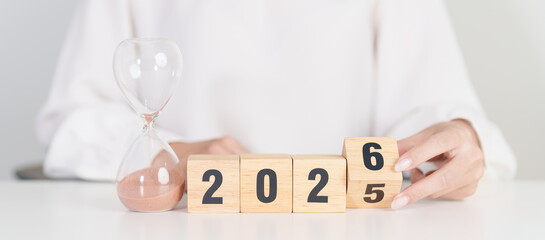 2025 end year to Happy New Year 2026 with hourglass on table. Resolution, time, plan, goal,...