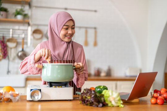 Muslim woman vlogger live streaming cooking online in kitchen look at camera with vegetables, content creator culinary class at home studio, halal food influencer cooking live, video for social media