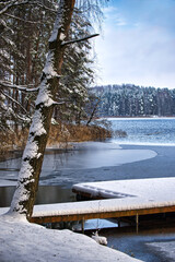 Snowy Lakeside Dock Scene With Snow-Covered Trees And Calm Frozen Water