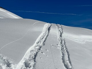 Wonderful winter hiking trails and traces in the fresh alpine snow cover of the Swiss Alps and over the village of St. Ant&ouml;nien - Canton of Grisons, Switzerland (Kanton Graub&uuml;nden, Schweiz)