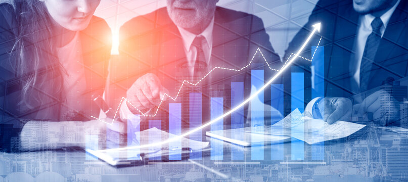 This image captures business professionals engaged in a collaborative meeting focused on financial growth analysis, featuring charts and data visualization. Impute - Powered by Adobe