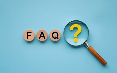 FAQ concept with magnifying glass and wooden blocks on blue background