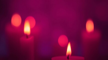 Burning candles glow with blurred lights in soft focus against a purple background.