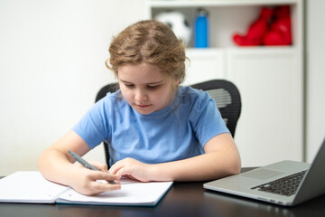 Remote school lesson. Teen student focused on homework at desk. Homeschooling with child writing. Kid writing notes while studying with laptop. Child education and learning concept.