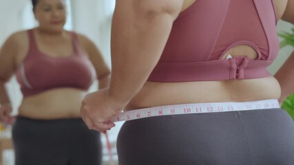 A plus-size woman who is confident in her body and lives a healthy lifestyle uses a tape measure to measure her waist after a workout.
Concept: Body positivity and self-love. - Powered by Adobe