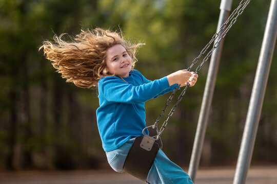 Excited child enjoying a fun ride. Happy kid on playground. Carefree kid swinging in the air. Happy children play outside. Blonde kid swinging with excitement. Playful kid outdoor. Funny kids face.