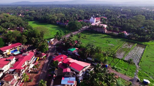 Houses with signal tower, lush greenery and Our Lady of Merces Church at Fatona, colva, goa, india. day time, push in shot, drone shot, 4k.