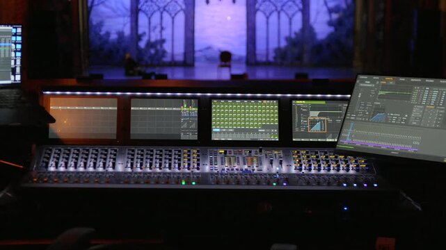 Wide view of modern audio mixing console with multiple digital screens in studio