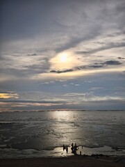 Sunset over Muddy Coastal Shore with Calm Water and Cloudy Sky