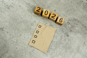Paper with goal text and wooden cube blocks with 2026 text on gray background. New Year 2026 idea concept.