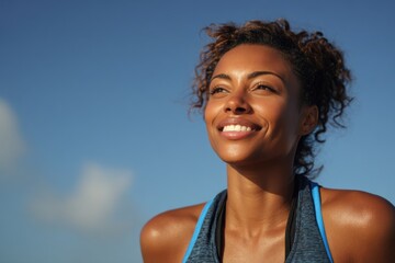Happy black woman smiles brightly after a successful workout during a sunny day outdoors, showcasing her athletic spirit and joy in fitness