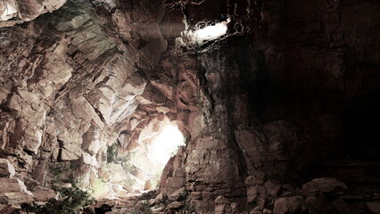 A breathtaking cave scene reveals rugged rock formations illuminated by natural light filtering through gaps above. The earthy tones and shadows create an enchanting atmosphere of discovery.