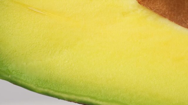 Static extreme macro of avocado flesh and seed texture. Detailed yellow pulp and brown pit background. Abstract healthy food concept.