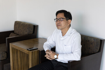 Asian businessman waiting for his colleague who is coming late and feeling bad about it