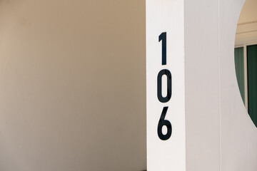 Close-up of minimalist signage for number 106 in modern building entrance design