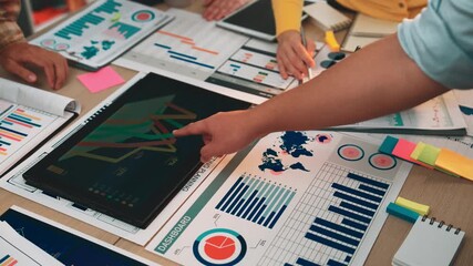 Group of diverse individuals collaborating on data analysis at office table, showcasing charts, graphs, and notes in a vibrant workspace, emphasizing teamwork and strategy. SACTR - Powered by Adobe