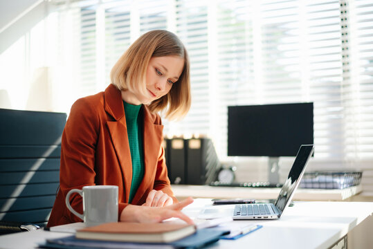 Business woman reviewing documents at desk in modern office. Ideal for finance, marketing, startup workflow, data analysis, productivity, and remote work themes.