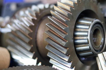 Close-up of a disassembled automotive transmission main shaft, featuring a series of stacked helical gears and synchronization rings, symbolizing complex mechanical engineering and vehicle repair.