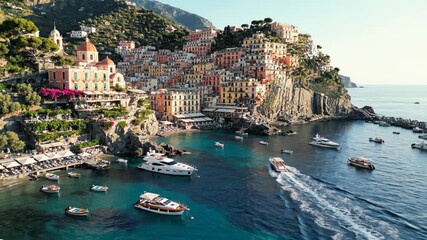 Aerial view of colorful amalfi coast town built into cliffside with boats and yachts in the clear blue mediterranean sea