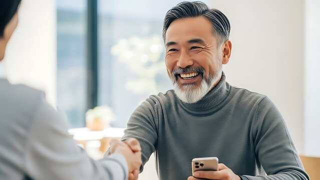 Smiling Asian businessman shaking hands with colleague in office meeting. - Powered by Adobe