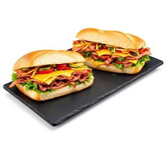 Two fresh sub-style sandwiches with deli meats cheddar shredded carrots and vegetables on black slate tray