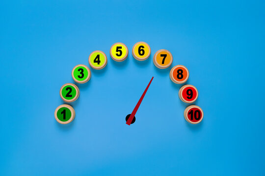 risk level meter indicator from low to high with 1 to 10 scale numbers on wooden blocks. isolated on blue background. concept of risk management